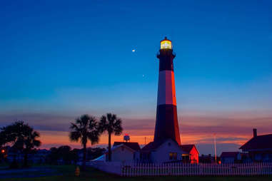 a lighthouse surrounded by palm trees at dusk