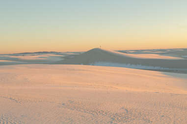 a person standing on a distant sand dune